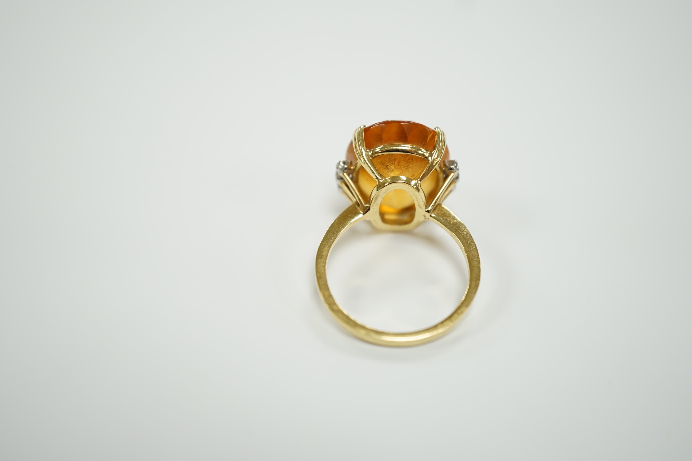 An 18k and single stone oval cut citrine set dress ring, with six stone diamond set shoulders, size R, gross weight 8.3 grams.